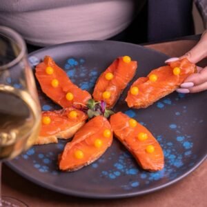 Plate of smoked salmon canapés with white wine, perfect for a sophisticated appetizer.